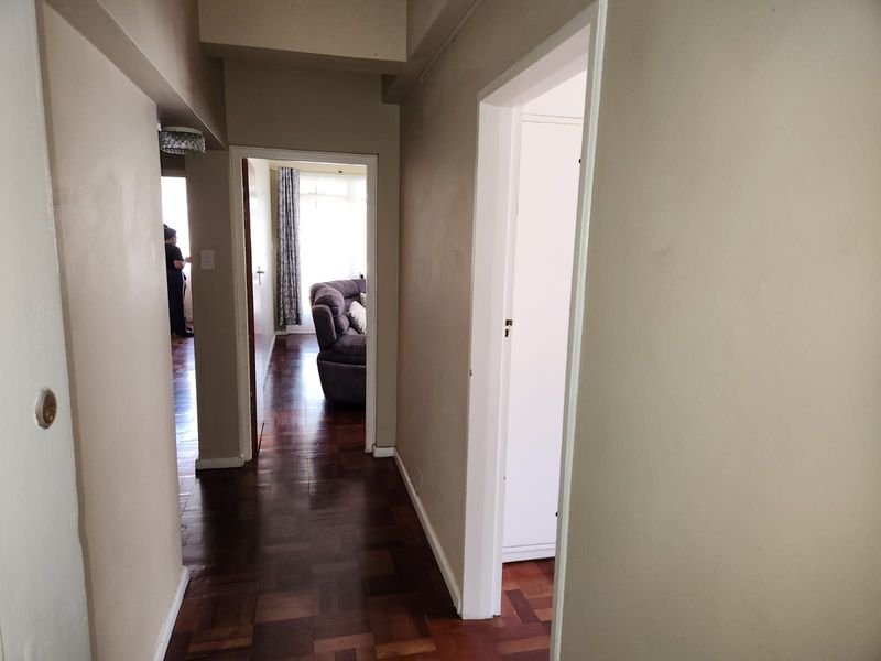 A functional hallway featuring traditional parquet flooring and access to adjacent living areas and built-in storage.