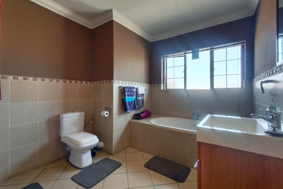 A functional bathroom featuring a built-in bathtub, a standard toilet, and a vanity basin with tiled walls and flooring.