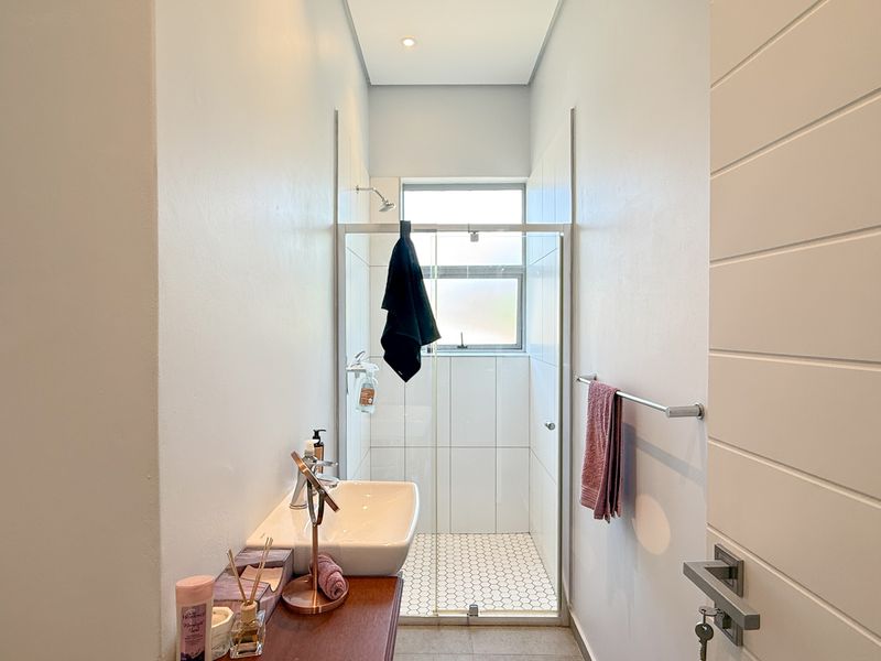 A clean, modern bathroom featuring a walk-in shower with a glass enclosure, a contemporary basin, and neutral wall finishes.