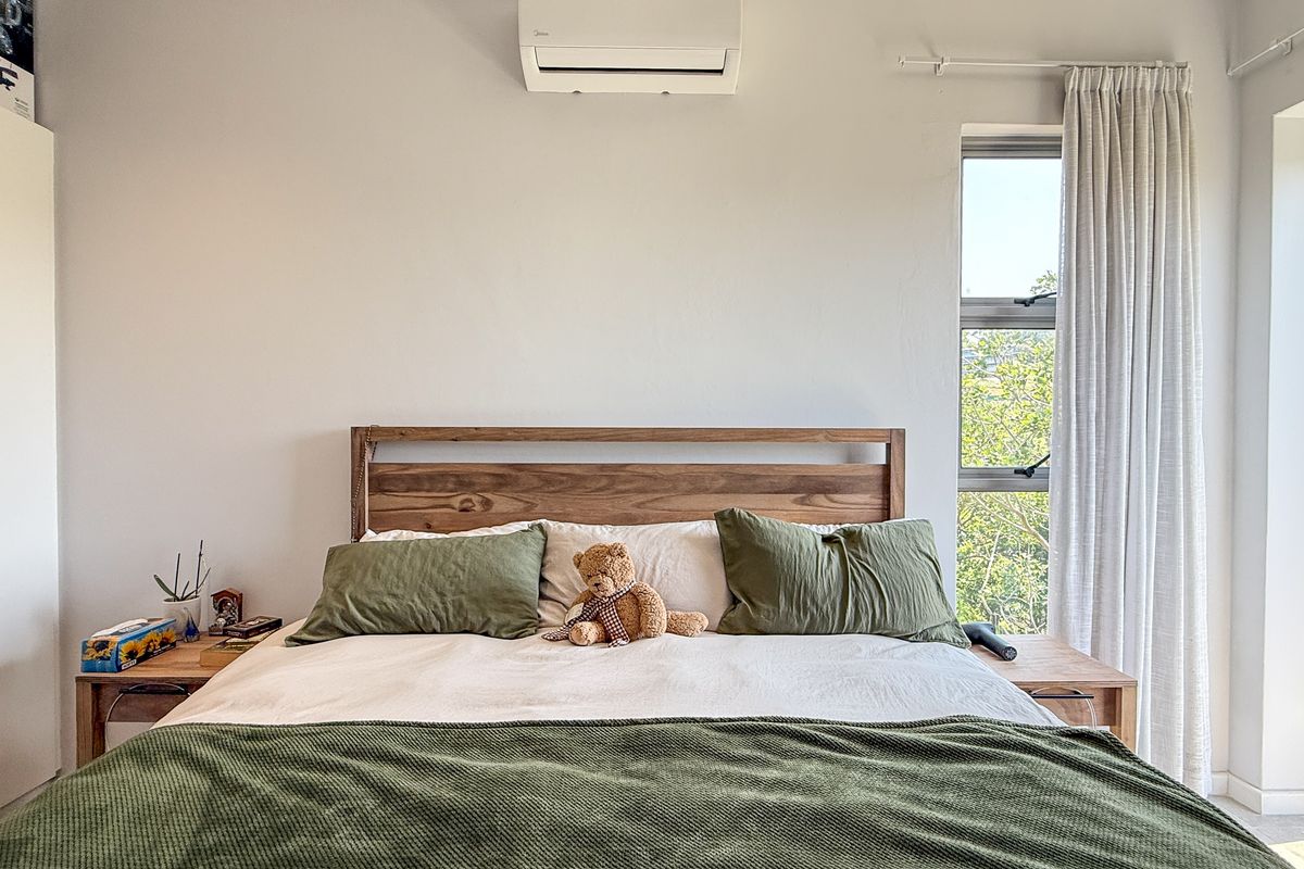 A well-maintained bedroom featuring a built-in wardrobe, split-system air conditioning, and direct access to an outdoor area through a sliding glass door.