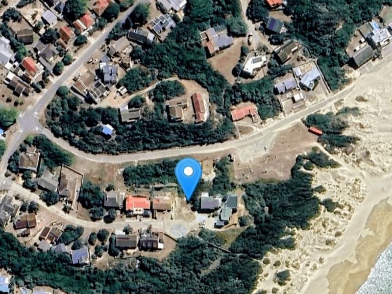 Aerial view of a vacant residential plot situated in a coastal neighborhood, offering proximity to the beach and surrounding residential infrastructure.