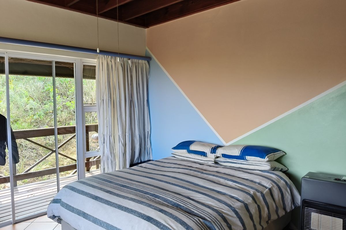 A bedroom featuring exposed timber ceiling beams, tiled flooring, and sliding glass doors providing access to an outdoor deck area.