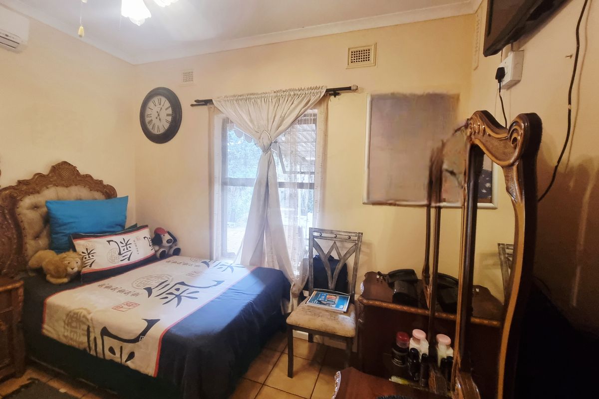 A bedroom featuring tiled flooring, a ceiling fan, and a window with curtain rod, providing a functional living space.