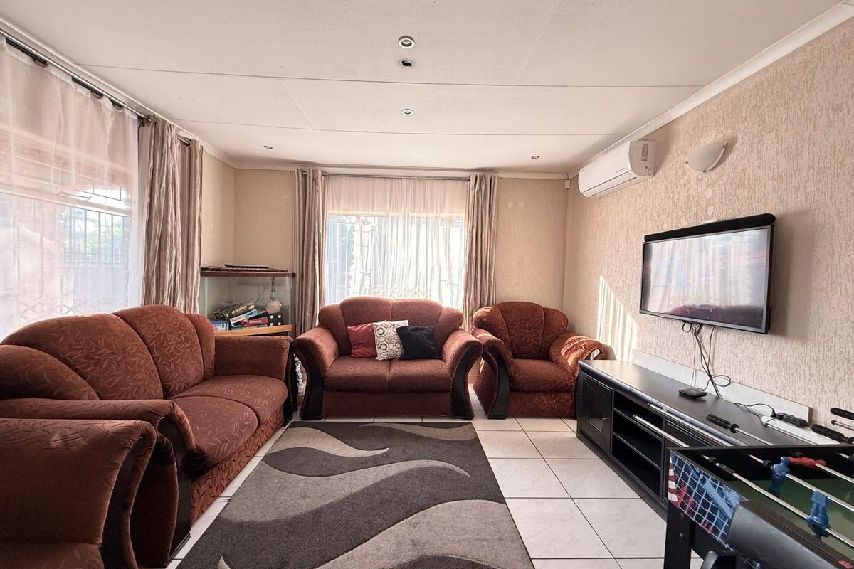 A comfortable living room featuring tiled flooring, wall-mounted air conditioning unit, and recessed ceiling lighting.