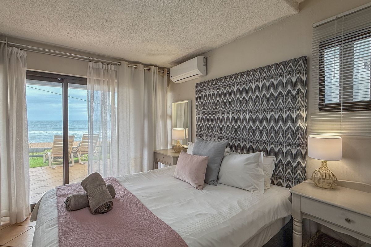 A bedroom featuring a wall-mounted air conditioning unit, sliding glass doors leading to a patio, and direct ocean views.