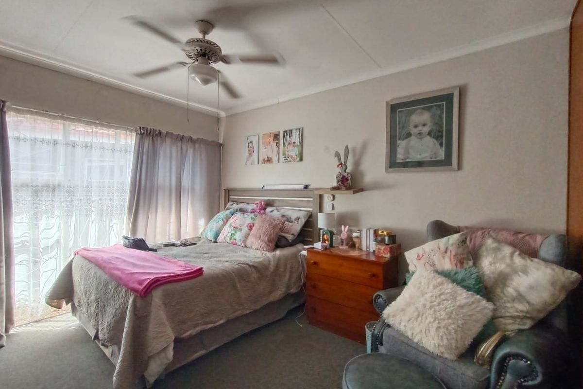 A bedroom featuring a ceiling fan, carpeted flooring, and a large window with curtains.
