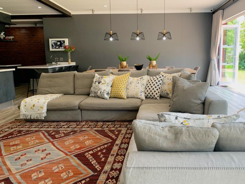 Spacious open-plan living and dining area featuring modern pendant lighting, exposed ceiling beams, and seamless access to the outdoors through bi-fold doors.