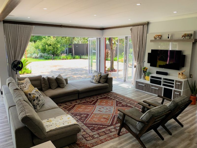 Spacious living room featuring modern laminate flooring, recessed downlights, and large bi-fold doors that open onto a landscaped garden patio.
