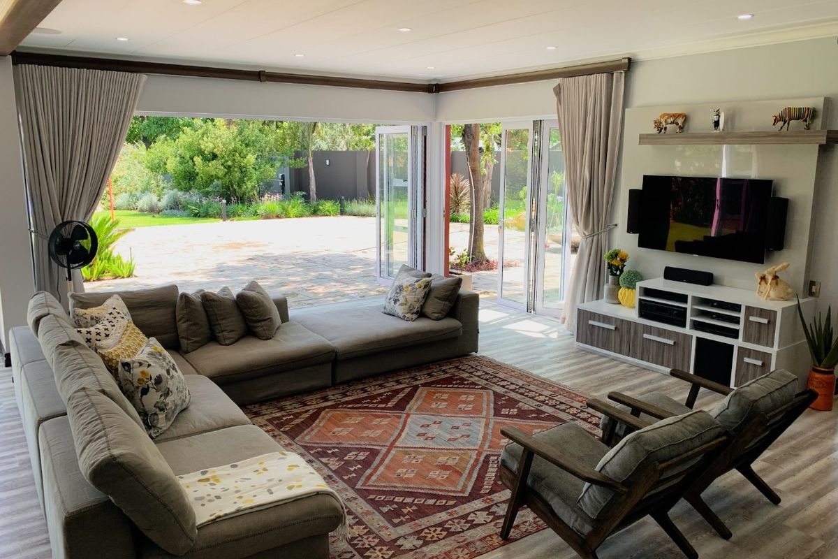 Spacious living room featuring modern laminate flooring, recessed downlights, and large bi-fold doors that open onto a landscaped garden patio.