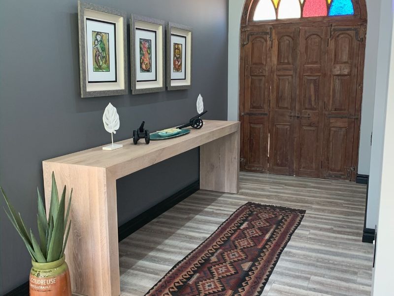 Welcoming entrance hall featuring a striking arched wooden double door with stained glass detailing and modern laminate flooring.