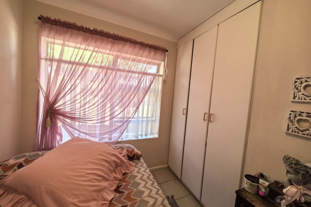 A bedroom featuring built-in floor-to-ceiling cupboards and a large window providing natural light.