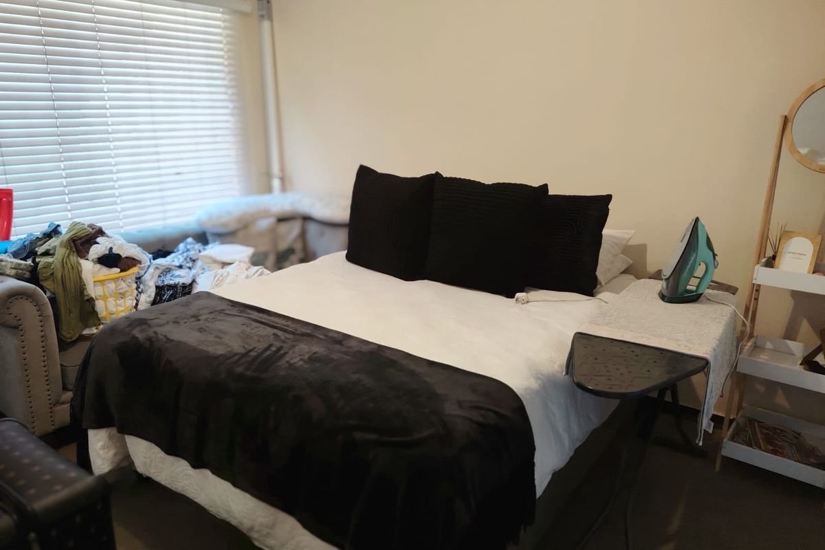 A bedroom featuring a window with fitted horizontal blinds and neutral wall finishes.