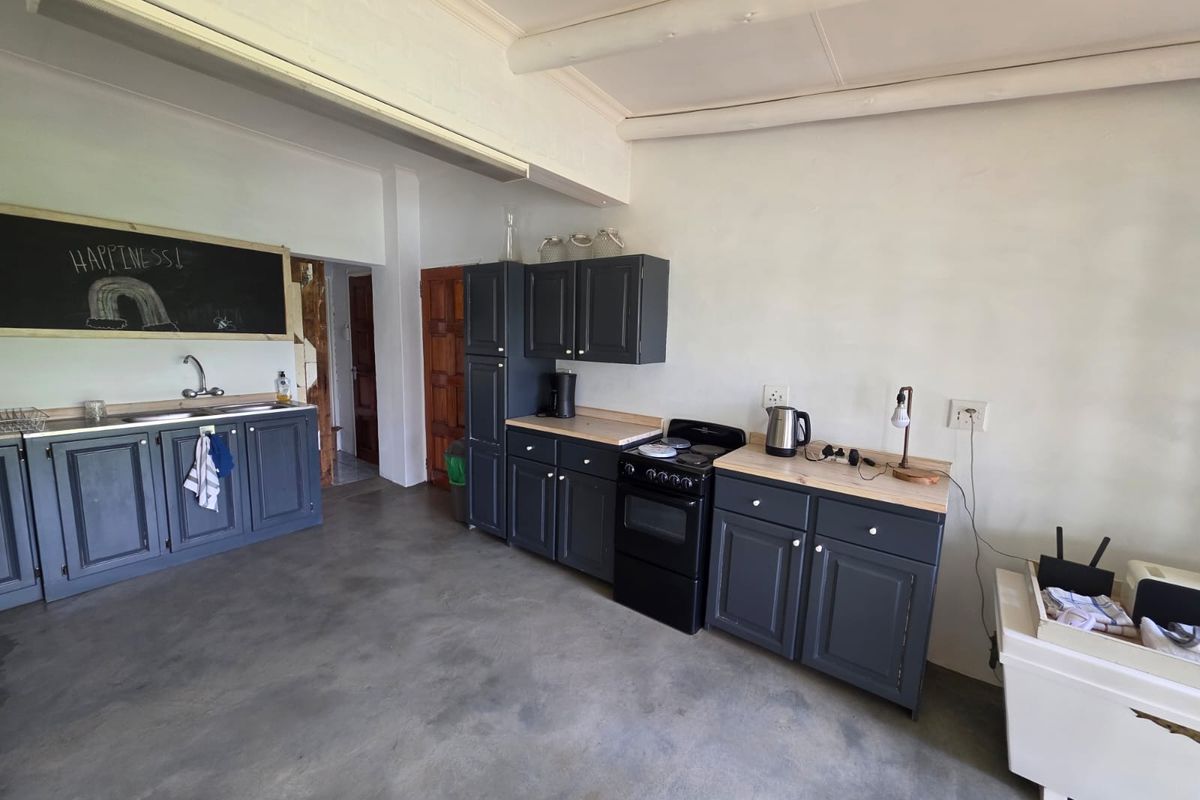 A functional kitchen area featuring dark grey cabinetry, a built-in stove, and a double sink, set against a neutral backdrop with concrete flooring.