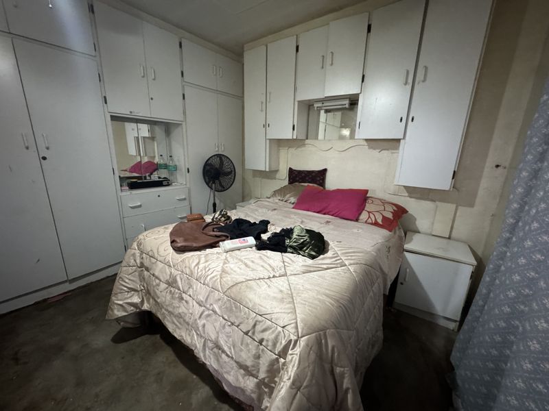 A bedroom featuring extensive built-in cabinetry and overhead storage units, offering significant potential for modernization and aesthetic improvement.