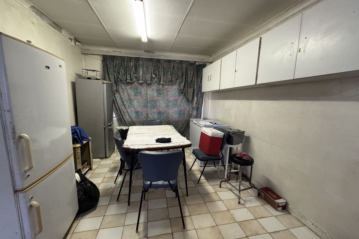 A dated kitchen area featuring built-in wall cabinetry, tiled flooring, and fluorescent lighting, currently in need of renovation and cosmetic updates.