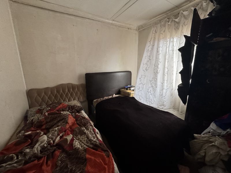 A bedroom featuring basic finishes, requiring cosmetic updates including wall and ceiling repairs to improve the overall condition and appeal of the space.