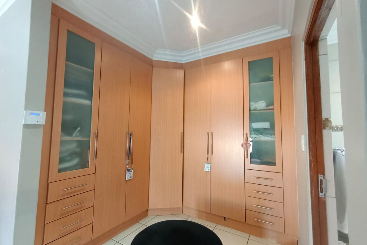 A bedroom featuring extensive built-in wooden cabinetry with integrated glass-panelled doors and drawers, providing ample storage space.