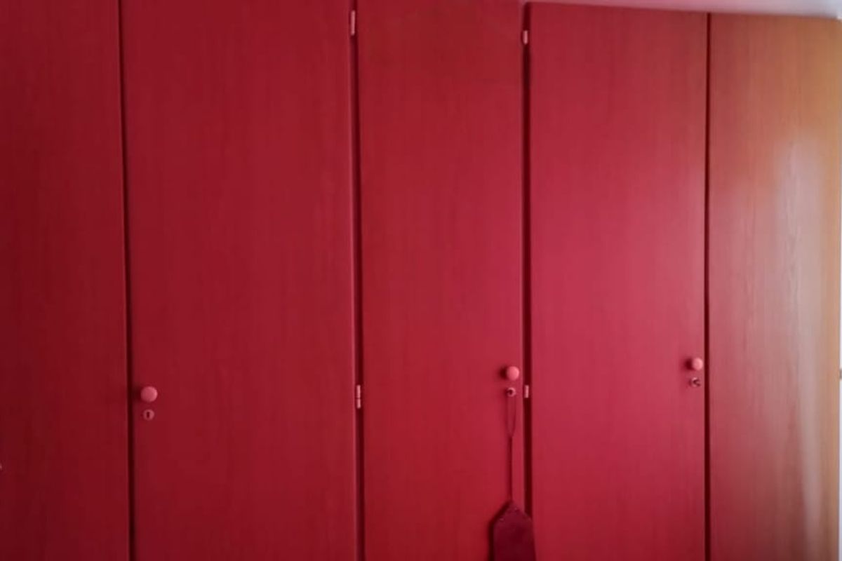 A bedroom featuring floor-to-ceiling built-in wooden wardrobes with a dated red finish.
