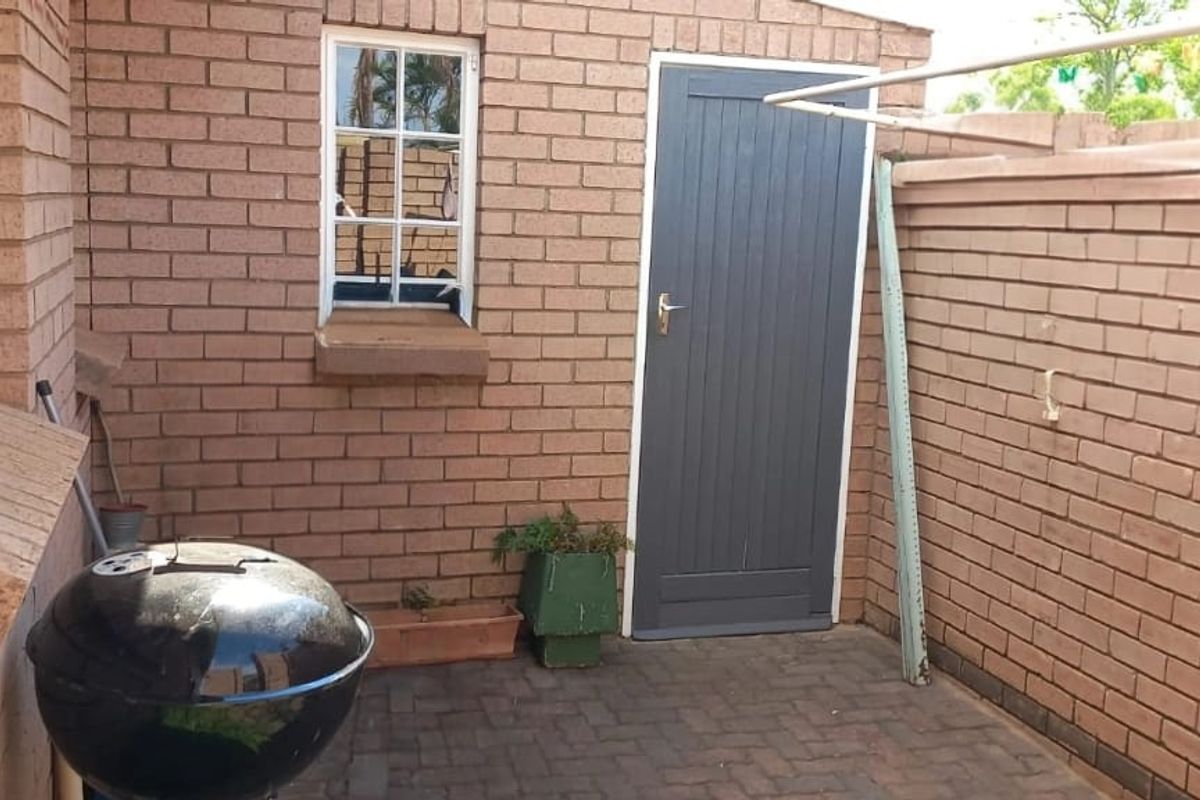 A private paved courtyard area featuring face-brick walls, a secure access door, and a wall-mounted clothes drying line.