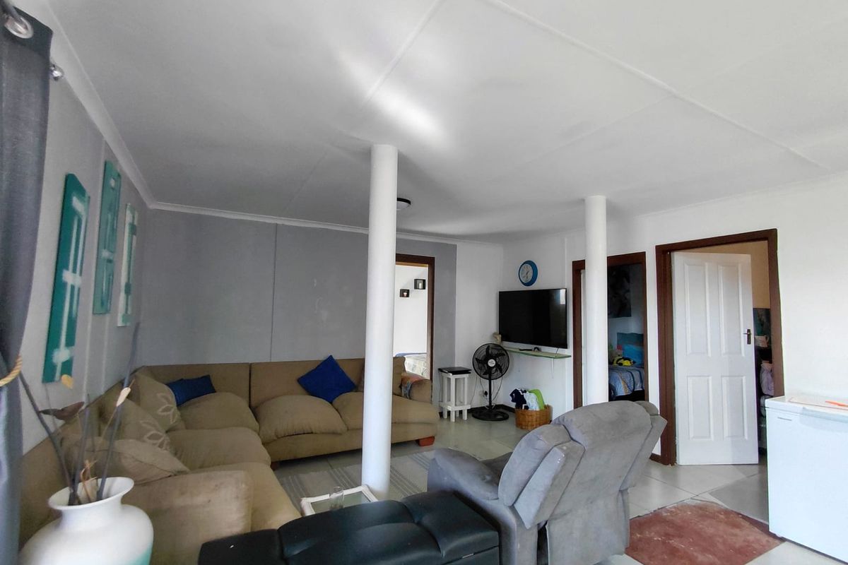 A living area featuring structural support columns, tiled flooring, and access to adjacent rooms through standard interior doors.