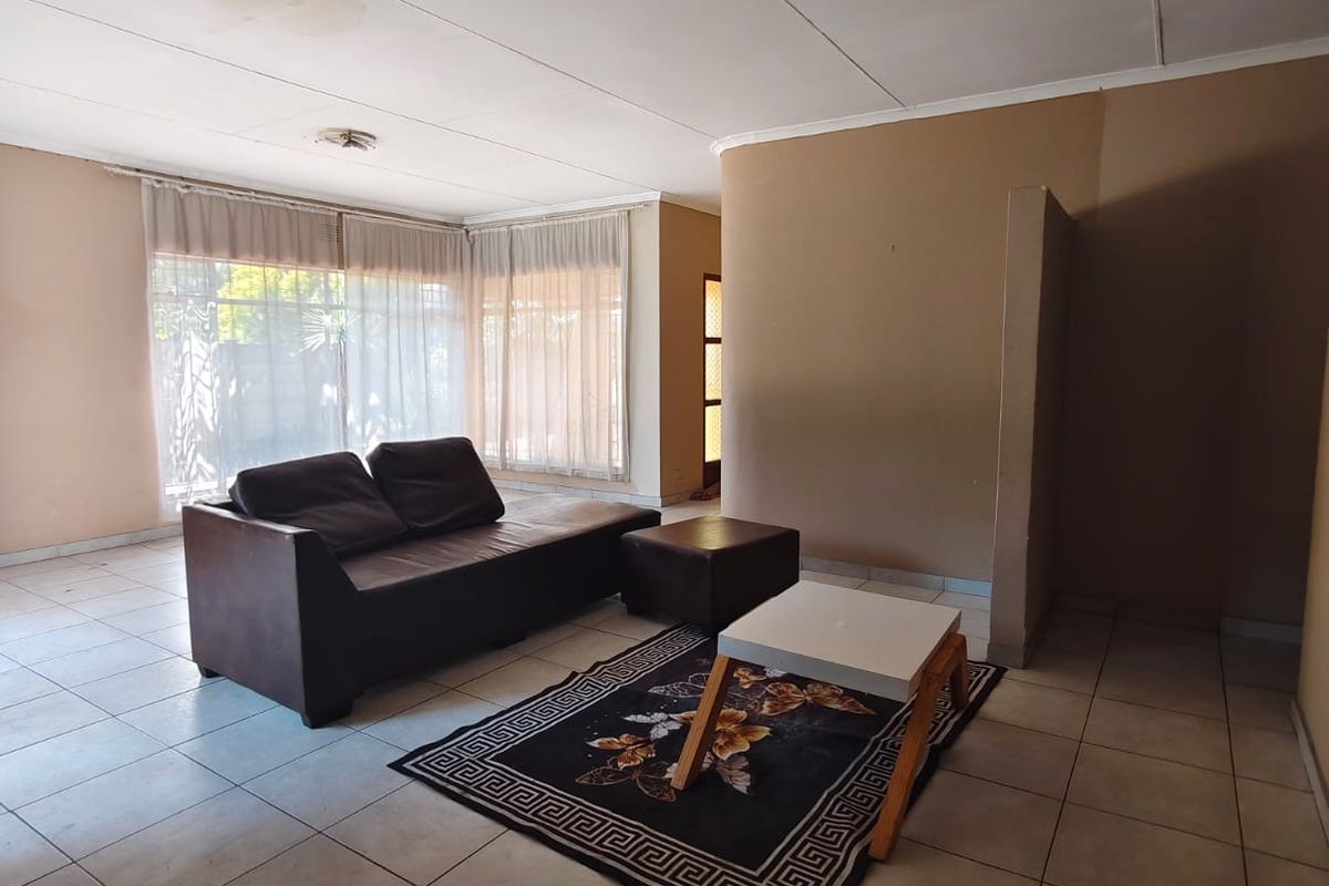 Spacious living area featuring tiled flooring and large windows, offering a blank canvas for renovation and interior design updates.