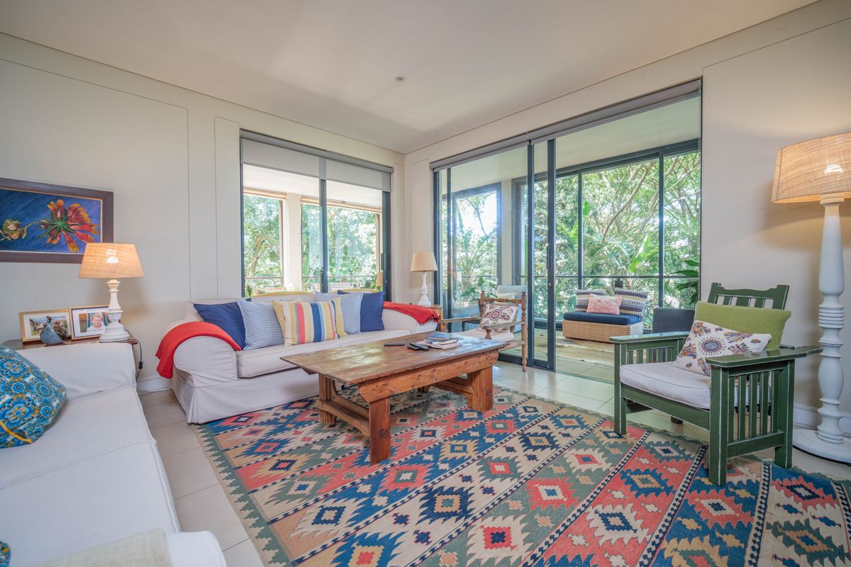 A bright living room featuring large sliding glass doors that open onto a private balcony, providing ample natural light and a view of greenery.