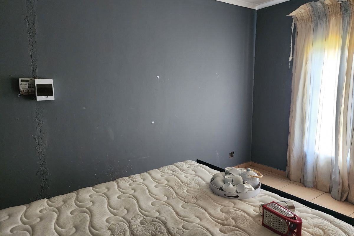 A bedroom featuring dark grey walls, tiled flooring, and a wall-mounted prepaid electricity meter.