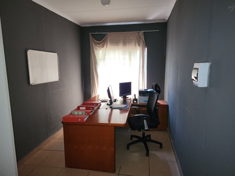 A functional home office space featuring tiled flooring and dark-toned walls, suitable for a dedicated workspace or study area.