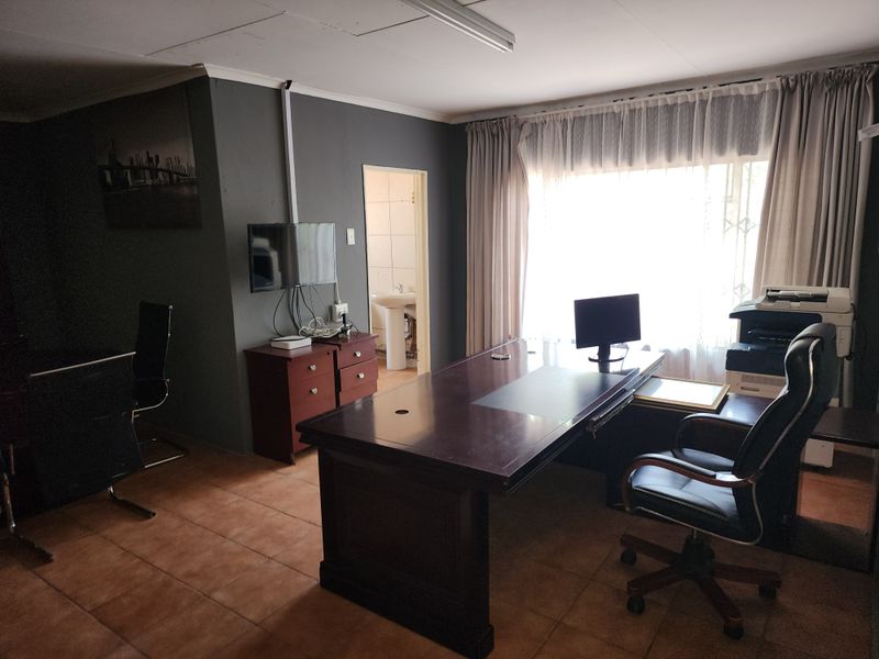 A functional home office space featuring tiled flooring, cove cornicing, and direct access to an adjoining bathroom facility.
