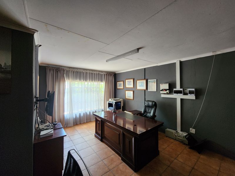 A home office space featuring tiled flooring, dark painted walls, and an installed inverter system, requiring some cosmetic updates to the ceiling and finishes.