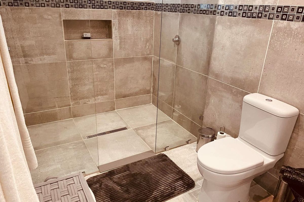 Modern bathroom featuring a walk-in shower with glass enclosure, built-in wall niche, and a standard white toilet.