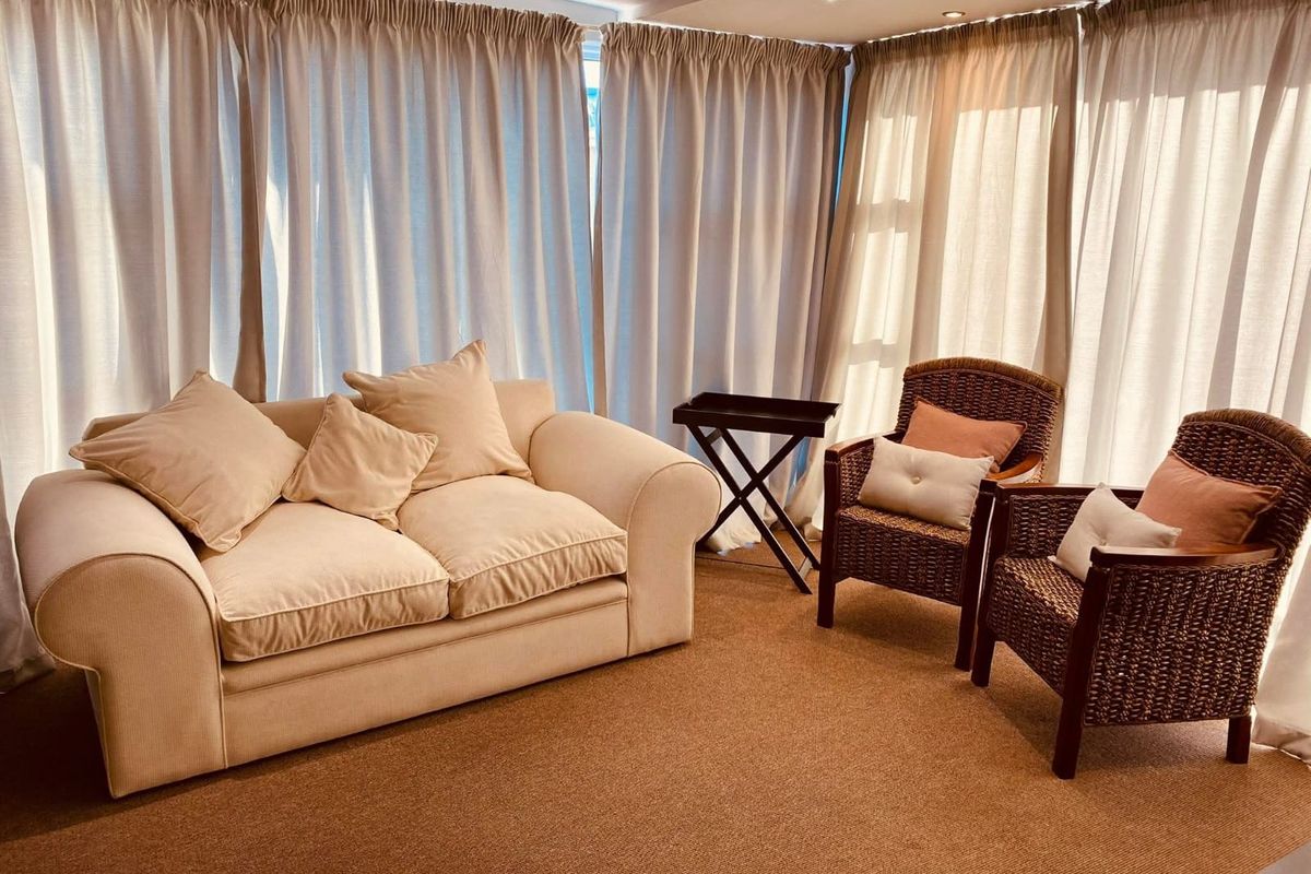 A bright living area featuring wall-to-wall curtains and neutral carpeting, providing a comfortable and well-lit space.