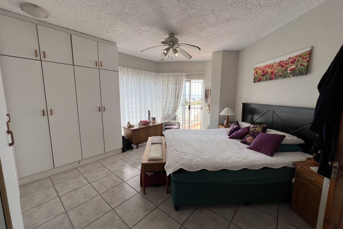 Spacious bedroom featuring built-in floor-to-ceiling wardrobes, tiled flooring, a ceiling fan, and direct access to a private balcony.