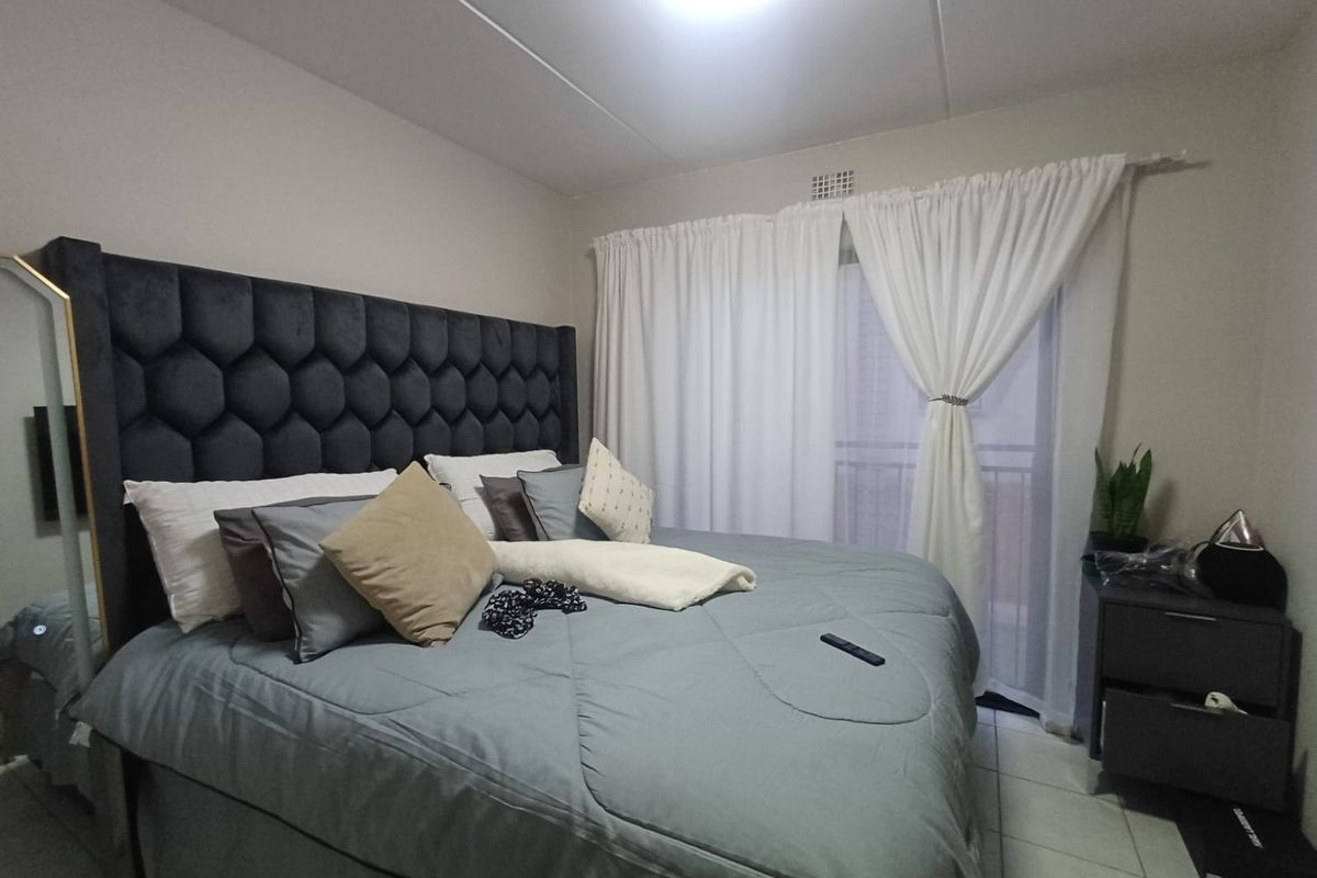 A bedroom featuring tiled flooring and a sliding glass door leading to a balcony, providing natural light and access to outdoor space.