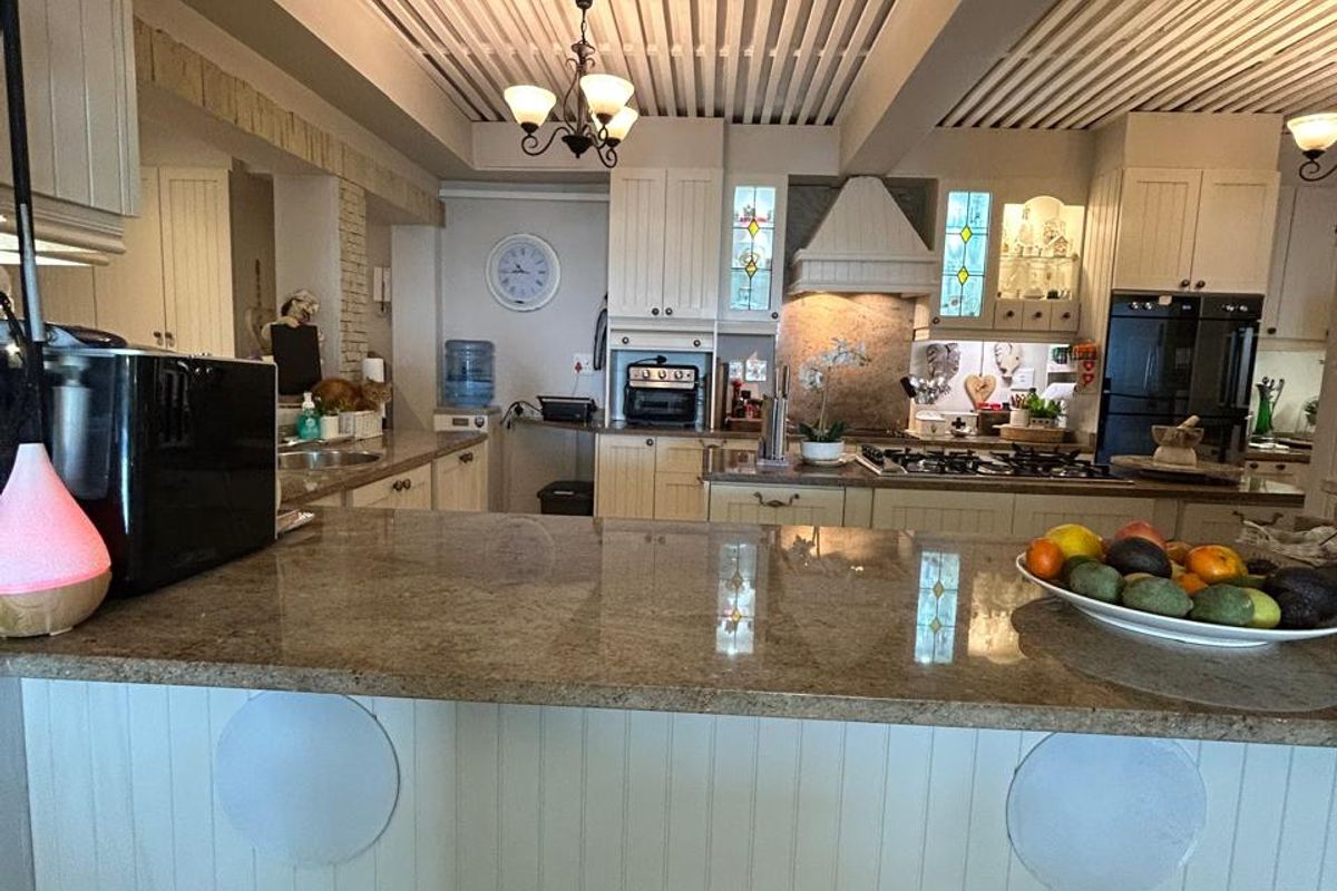Spacious kitchen featuring granite countertops, a breakfast bar, built-in oven, gas hob, and distinctive slatted ceiling design.