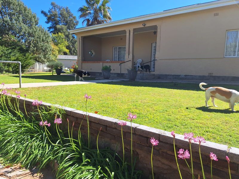 Front view of a townhouse featuring a covered patio, a brick retaining wall, and a well-maintained lawn area.