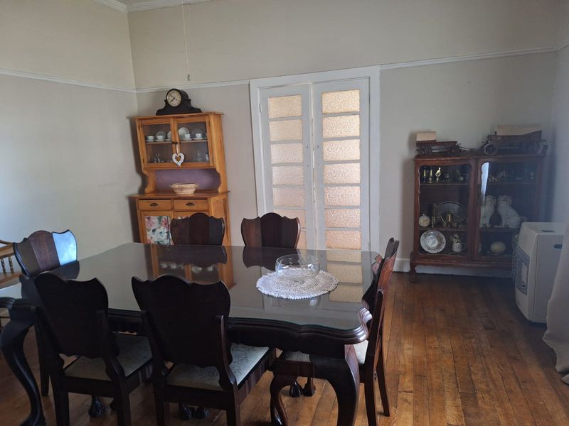 A traditional dining room featuring original hardwood flooring, picture rails, and classic French doors, offering a character-filled space for family meals.