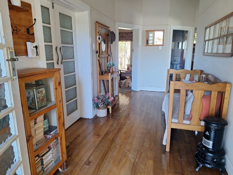 A traditional hallway featuring original hardwood flooring and classic frosted glass panel doors, providing access to adjacent living areas and a bathroom.