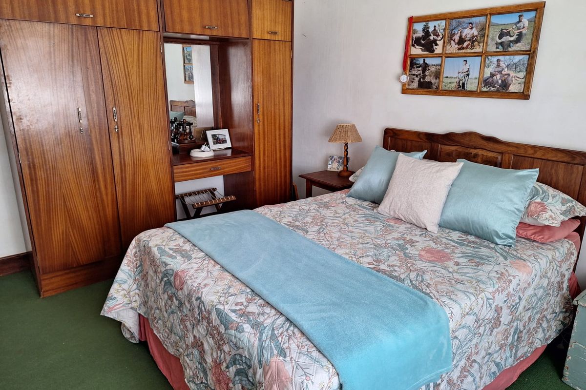 A bedroom featuring a large built-in wooden wardrobe with an integrated vanity mirror and carpeted flooring.
