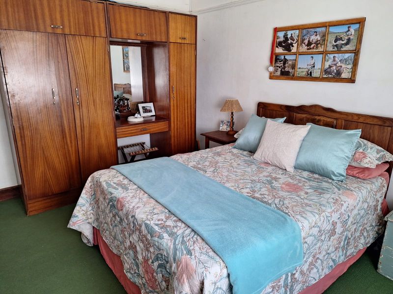 A bedroom featuring a large built-in wooden wardrobe with an integrated vanity mirror and carpeted flooring.