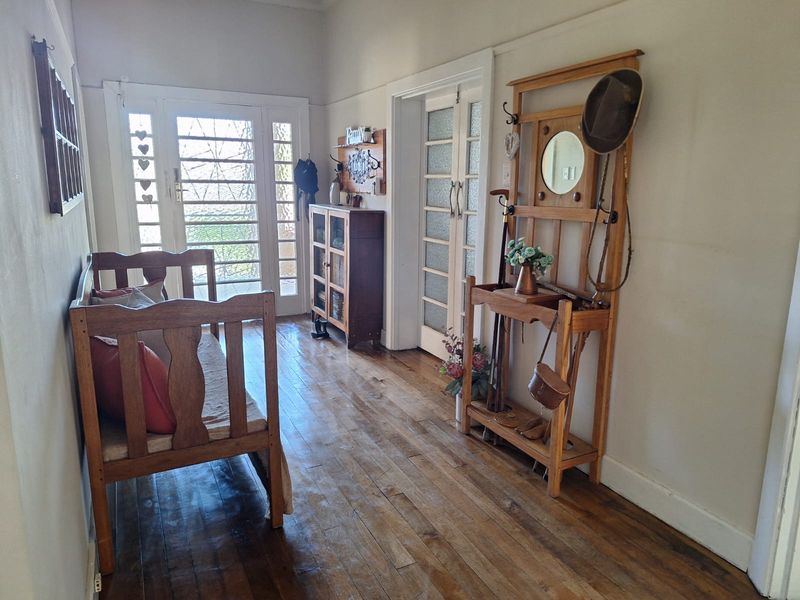 A welcoming entrance hall featuring warm hardwood flooring and classic glass-panelled doors that allow natural light to flow through the space.