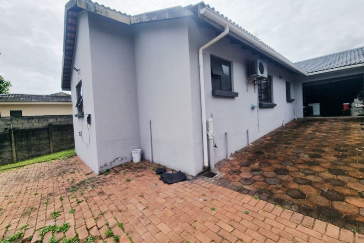 Exterior view of the side of the house featuring paved driveway, external air conditioning unit, and guttering system.