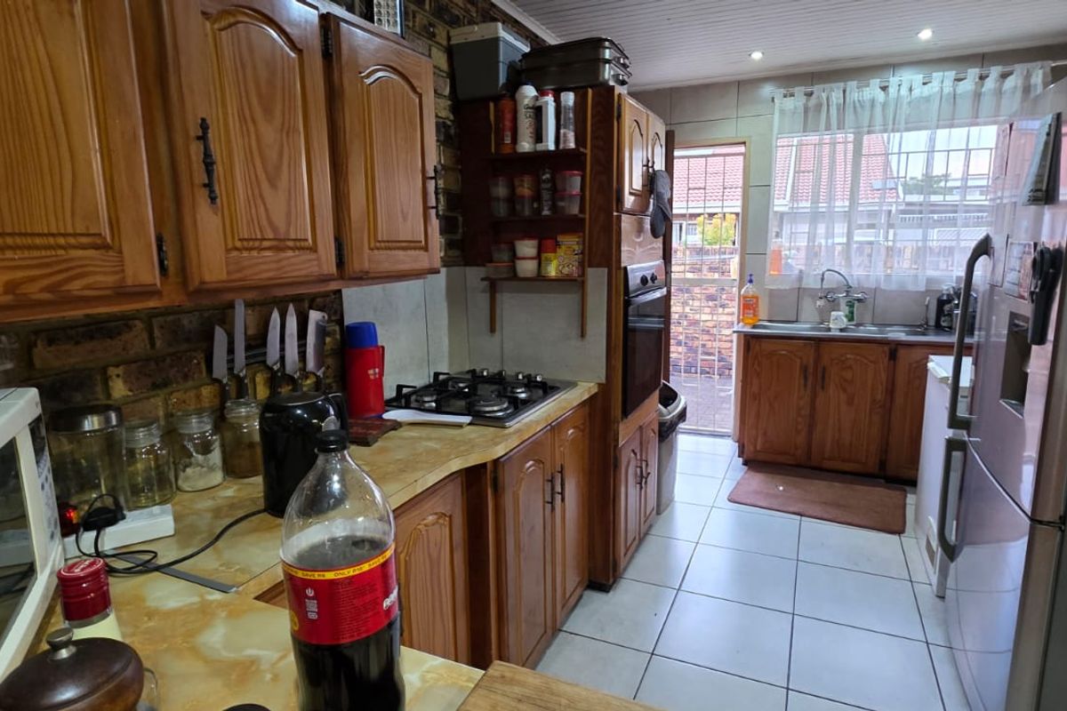 A functional kitchen featuring wood-finish cabinetry, a built-in gas hob, an integrated oven, and tiled flooring with direct access to the exterior.