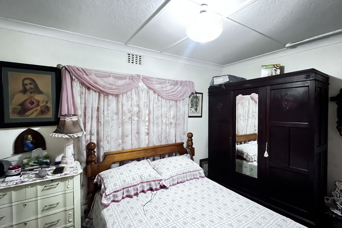 A bedroom featuring a ceiling with visible panel joints and surface-mounted electrical wiring, providing a functional sleeping space.