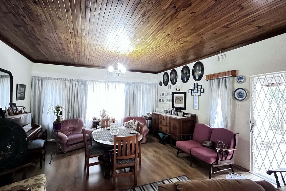 Spacious living and dining area featuring a distinctive wooden tongue-and-groove ceiling, laminate flooring, and direct access to the exterior through a security gate.