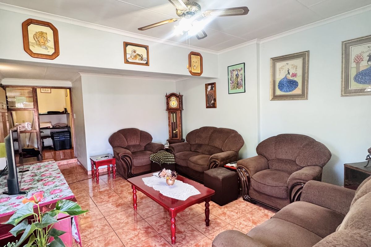 A spacious living room featuring tiled flooring and a ceiling fan, providing a comfortable area for relaxation and family gatherings.