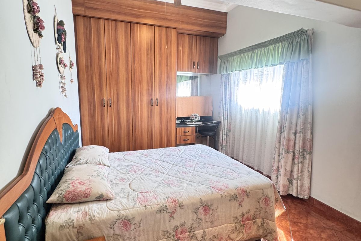 A bedroom featuring built-in wooden cabinetry, a vanity area, and tiled flooring, offering a functional layout with natural light.