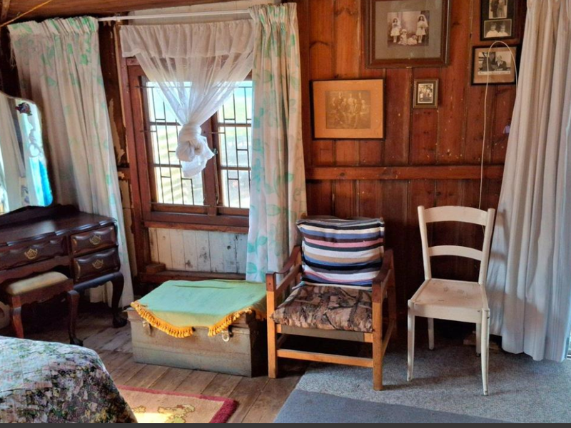 A bedroom featuring rustic timber wall paneling, a timber-framed window, and a security gate leading to the exterior.