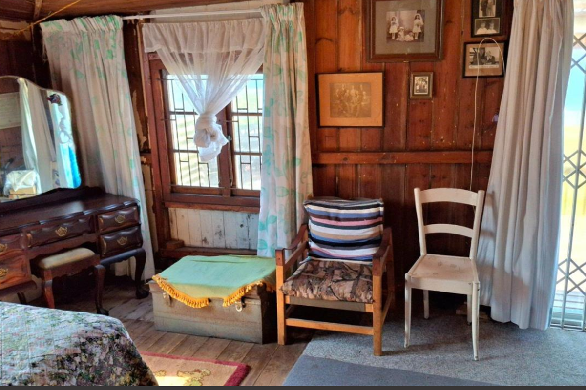 A bedroom featuring rustic timber wall paneling, a timber-framed window, and a security gate leading to the exterior.