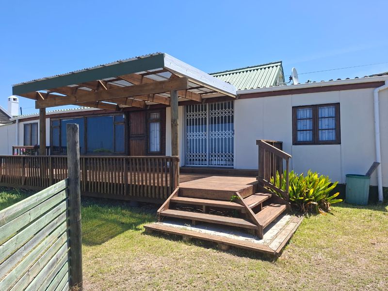 Rear exterior view featuring a timber deck with a pergola, security gate access, and a corrugated roof structure.